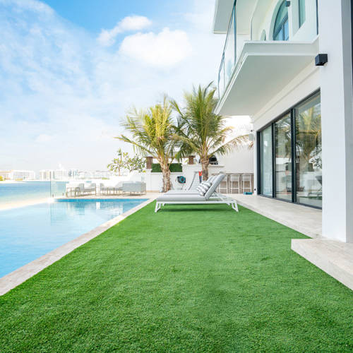 artificial grass in back garden with pool and deck chair during sunny day