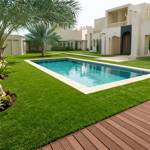 bahia artificial grass turf surrounding pool in white villa garden