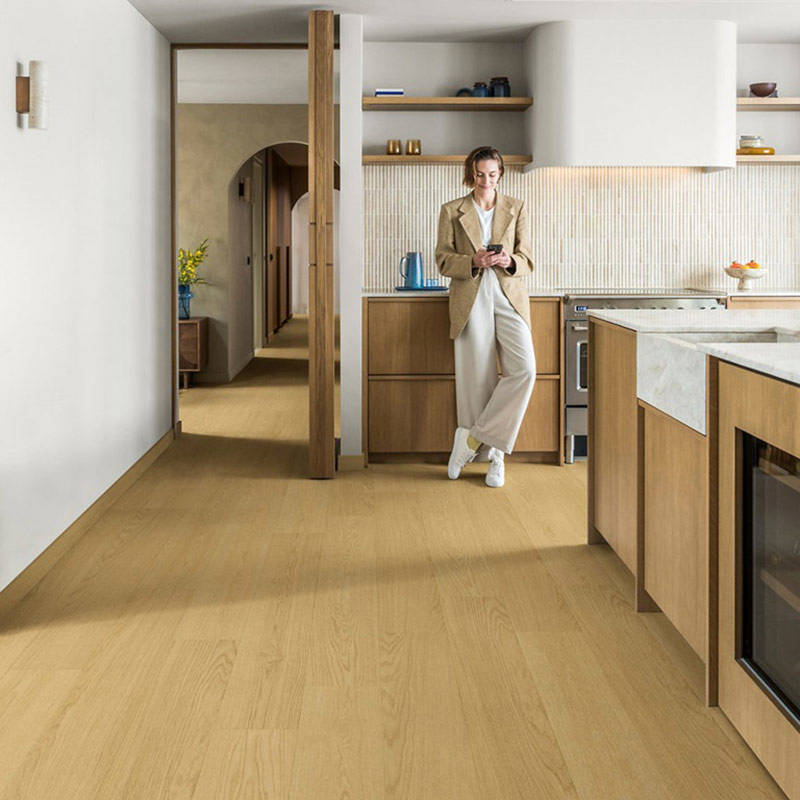 woman standing in open plan kitchen space with quick step impressive dune oak laminate