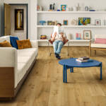 quick step impressive truffle oak laminate flooring in living space with reading man