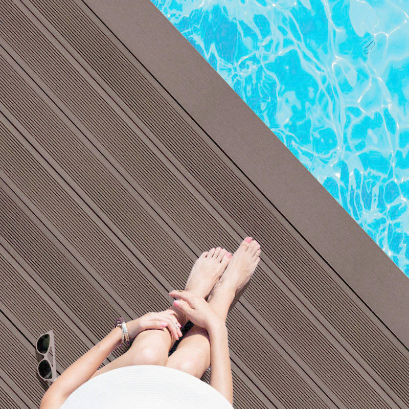 woman sitting on chocolate brown smart decking next to pool