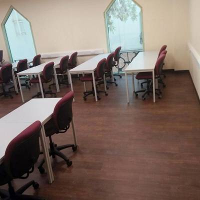 dark wooden flooring with desks and seats with white walls in sharjah university classroom